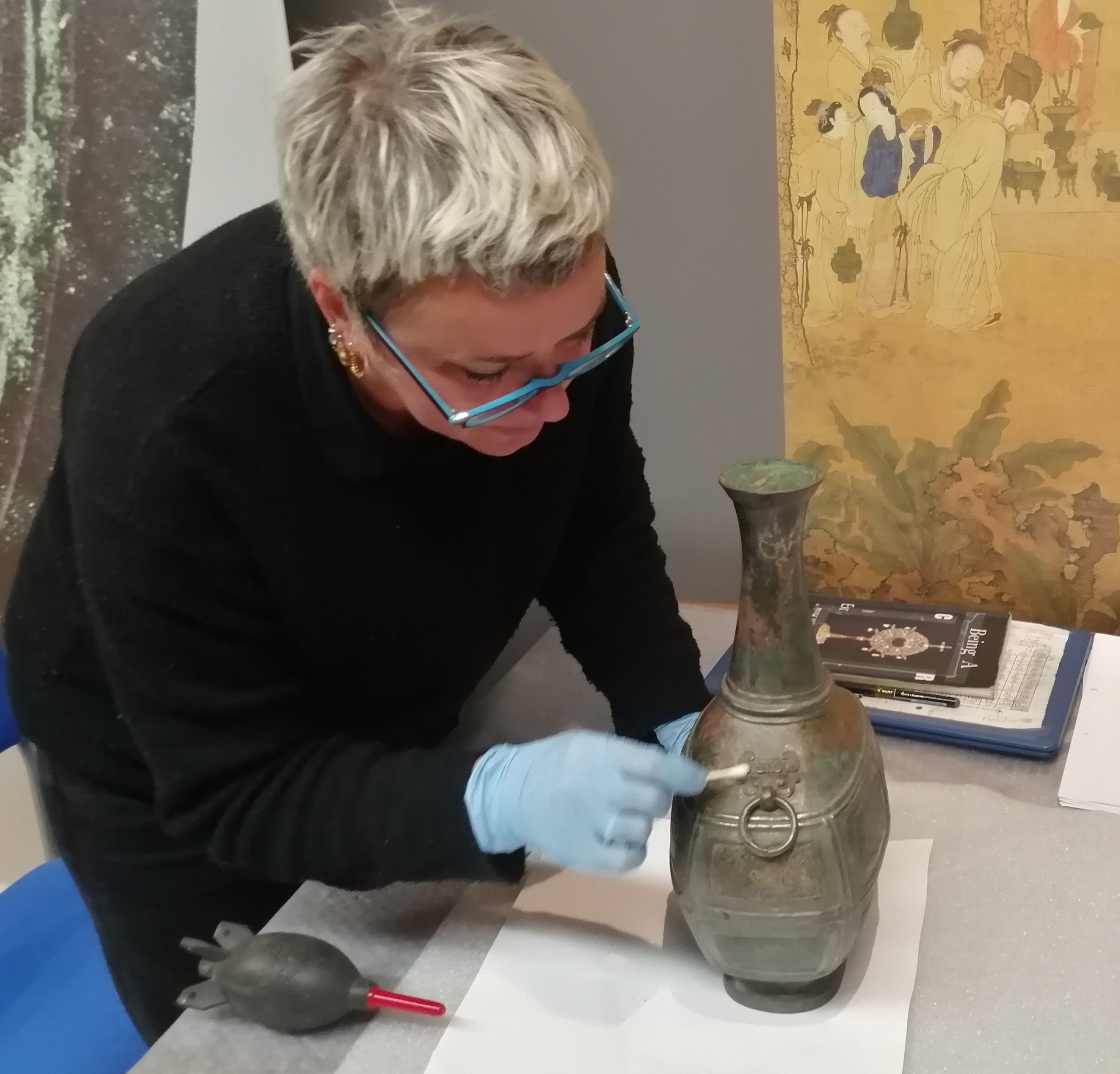 A conservator assessing a bronze object