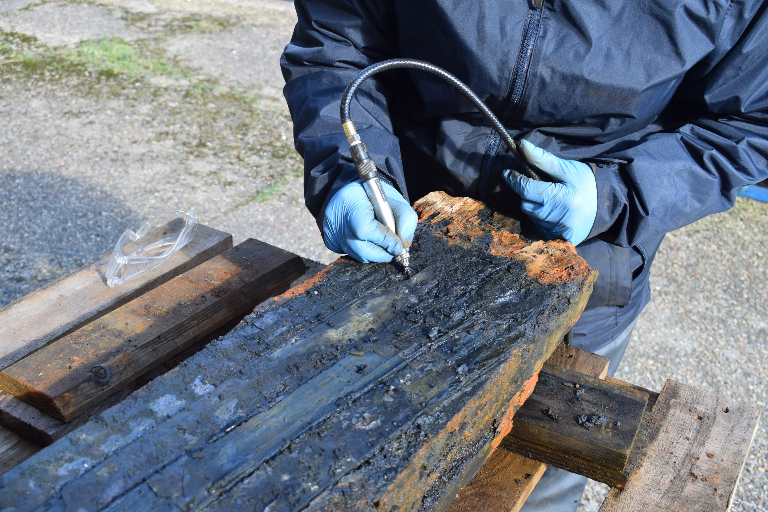 A conservator cleaning corroded metal